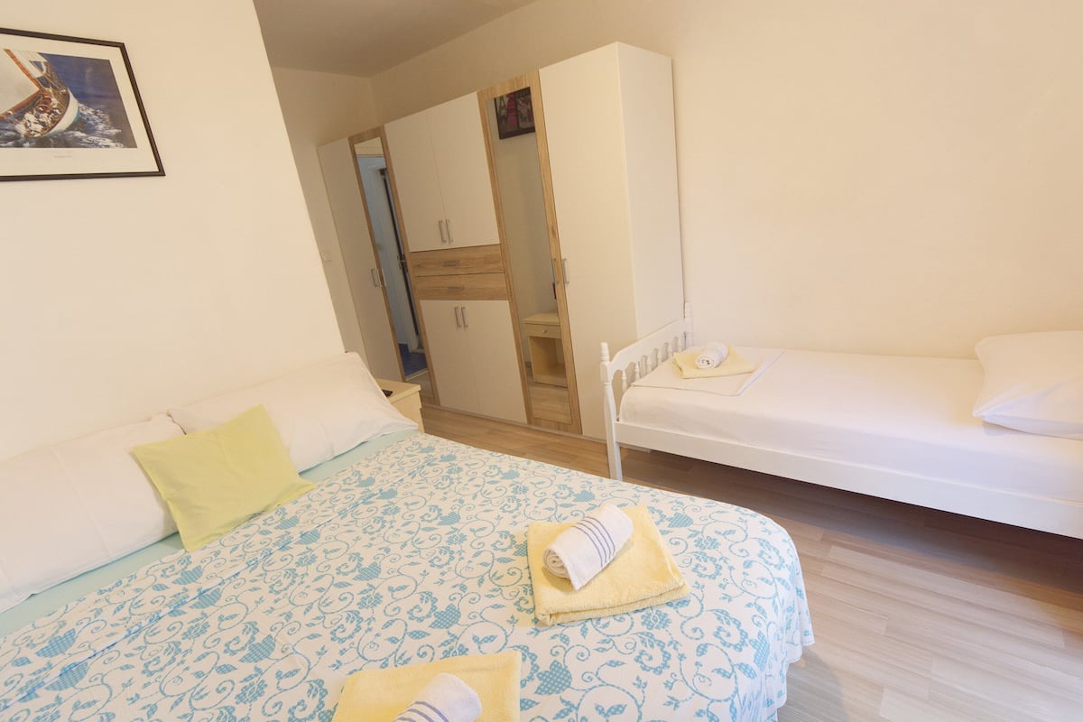 Een slaapkamer met een bed, nachtkastje, garderobe en een kleine kitchenette.