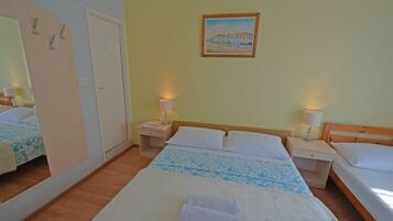 A hotel room with two beds, a wooden headboard, bedside lamps, a painting on the wall, and a mirror.