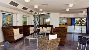 Ein stilvoller Lounge-Bereich mit Korbsesseln und Glastischen, eine Bar im Hintergrund und Blick durch die Glaswand.