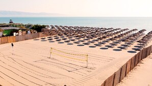 Ein Beachvolleyballfeld mit Netz, umgeben von Strandstühlen und einem Holzzaun.