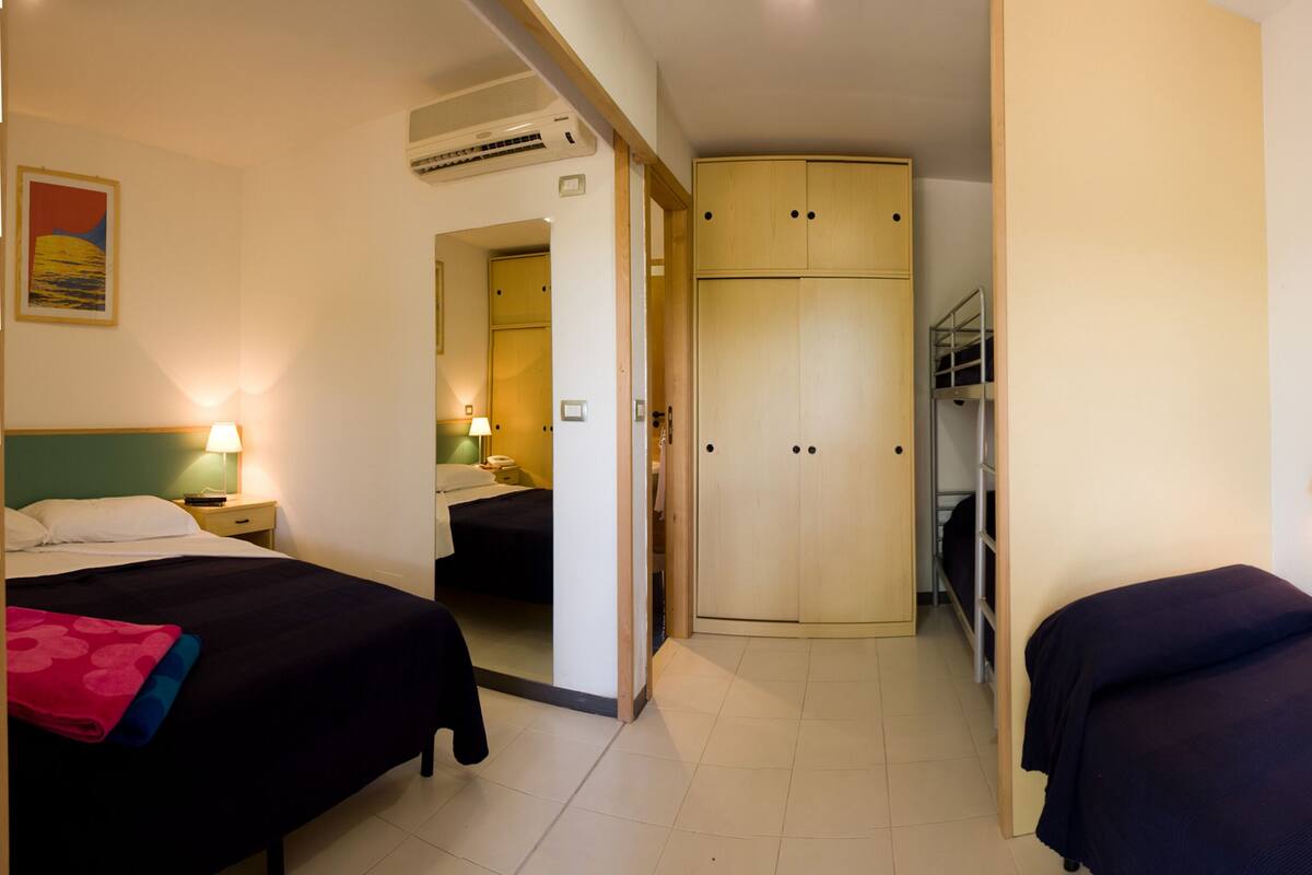 Habitación de hotel con dos camas, un armario, un espejo y una litera.