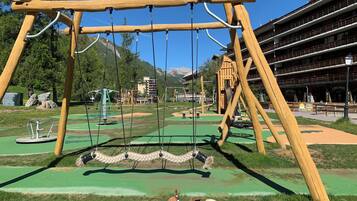 Relax in the serene outdoor space with a wooden swing set and rope swing, surrounded by lush greenery and breathtaking mountain views.