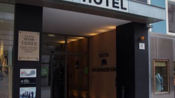 A hotel entrance with a sign reading "HOTEL" and flags above.