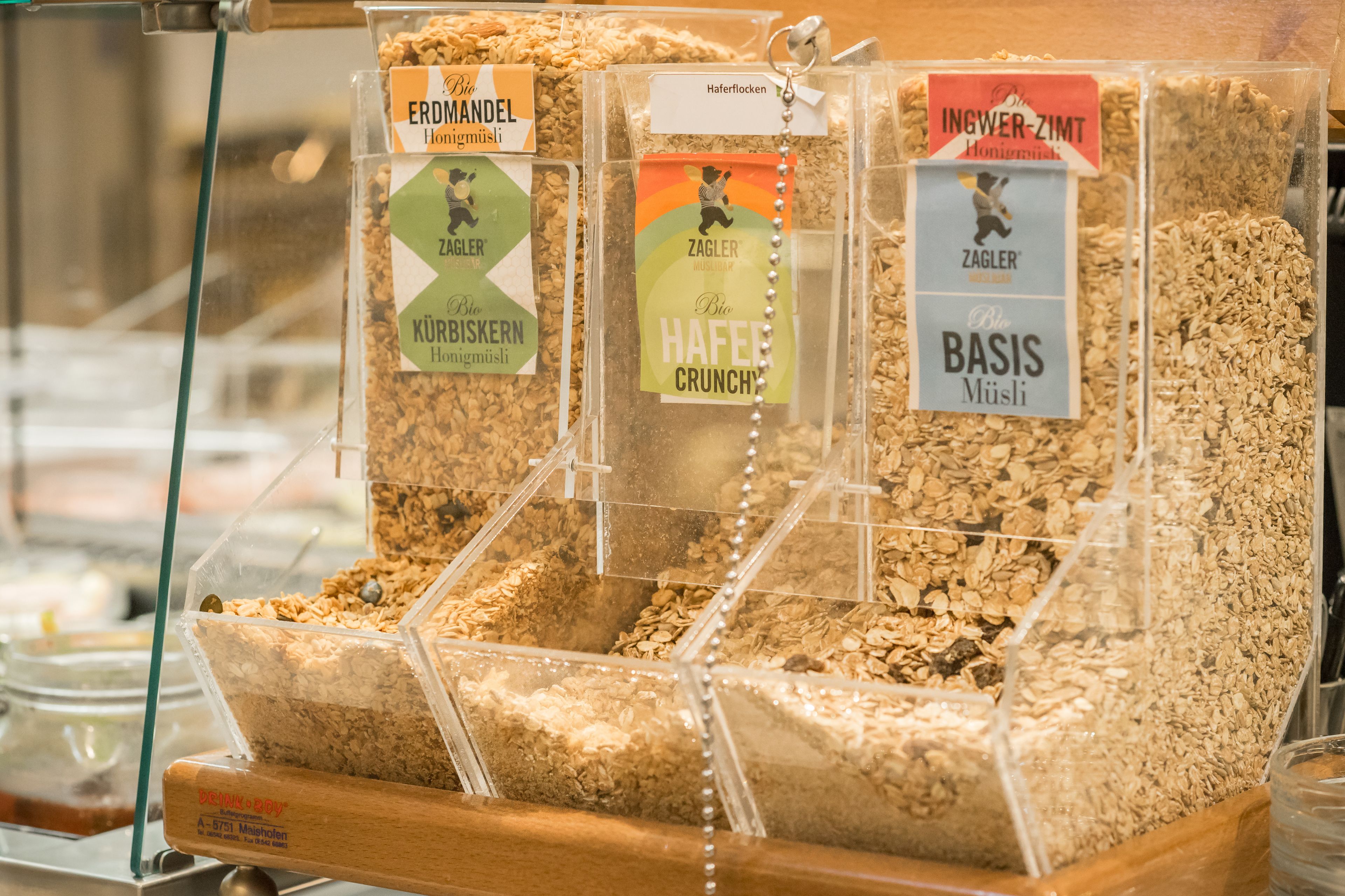 Esillä on granola-patukoita läpinäkyvissä muovirasioissa, joissa on etiketit.