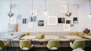 A modern interior with a sofa, tables, and chairs arranged for dining. - Hotel Schwarzer Bär (Linz)