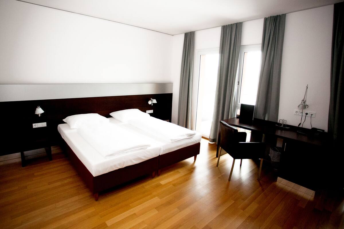 Quarto de hotel com uma cama grande, uma mesa e uma cadeira.