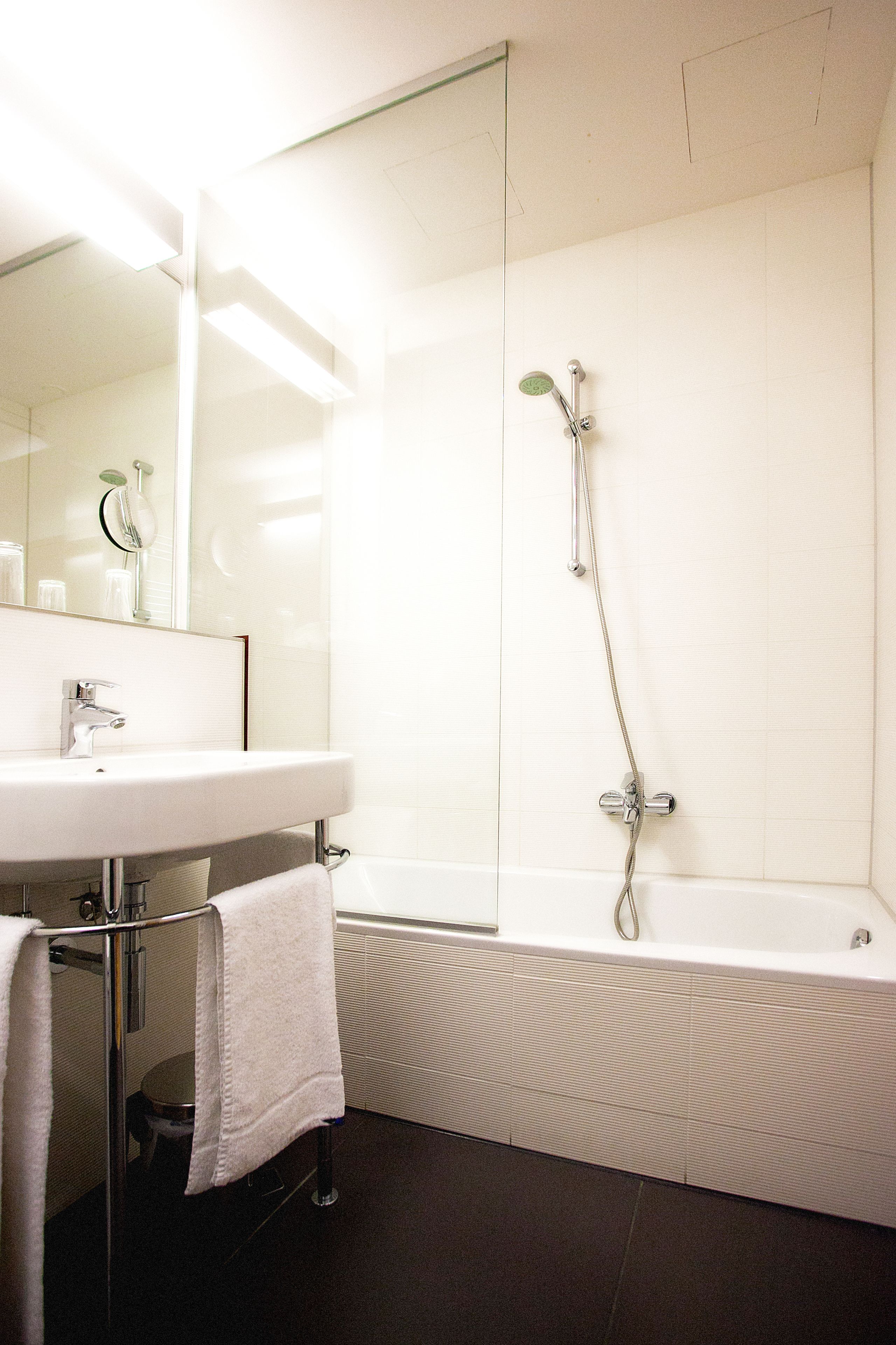 Ein modernes Badezimmer mit einem weißen Waschbecken, Spiegel und Dusche.