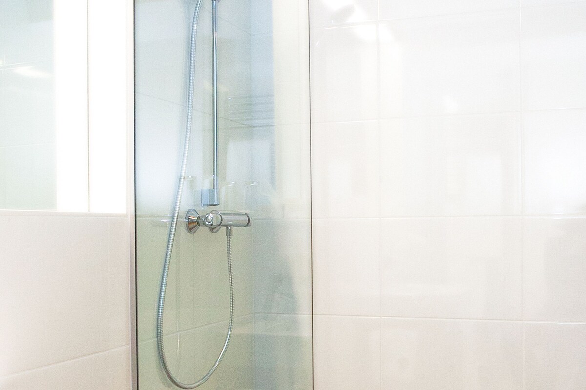 A bathroom with a glass shower enclosure, a white sink, and a towel rack.