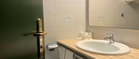Une salle de bain avec un lavabo, un miroir, un porte-serviettes et une porte verte.