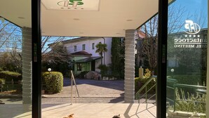 Ein Hotel Eingang mit einer grünen Matte, ein liegender Hund und ein sitzender Hund.