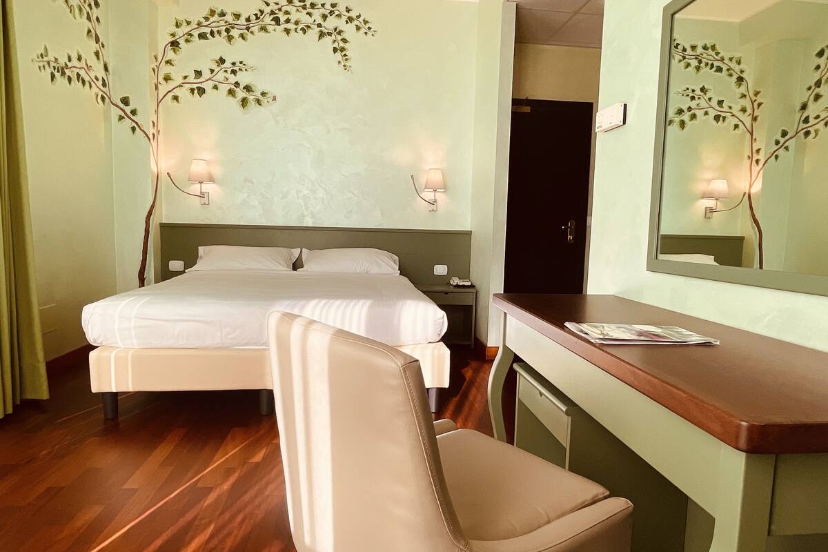 Een hotelkamer met een bed, een bureau, een stoel en een spiegel.