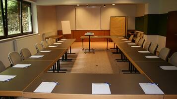 A conference room with a long table, chairs, a projector screen, and a whiteboard.