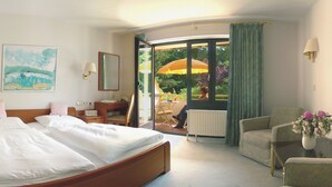 A hotel room with a bed, a desk, a chair, a window, and a view of the outdoors. - Parkhotel Hitzacker (Hitzacker)