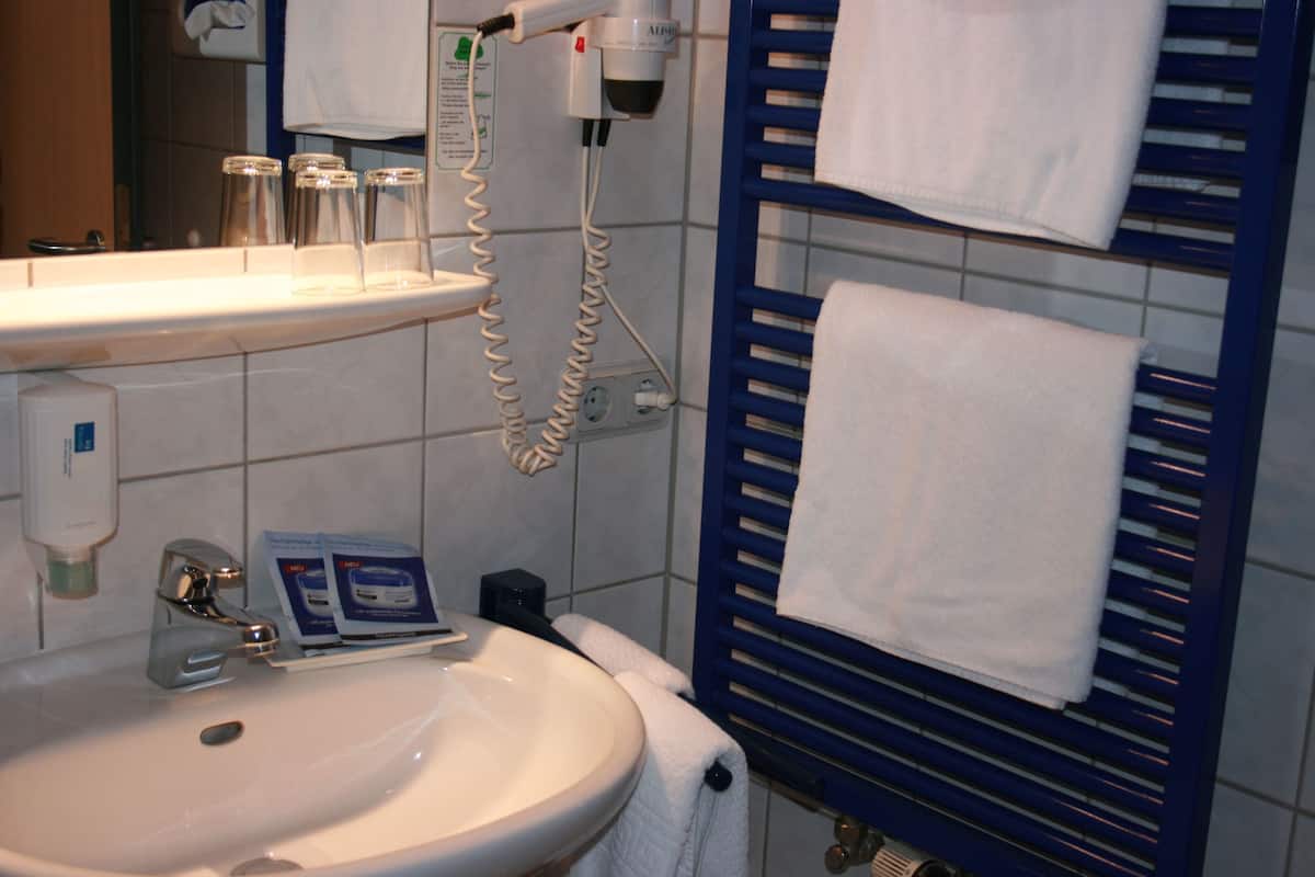 Un baño con lavamanos, espejo y perchero para toallas.
