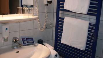 Un baño con lavamanos, espejo y perchero para toallas.