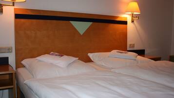 A hotel room with two beds, a wooden headboard, and wall-mounted lamps.