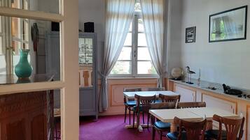 Un comedor con una mesa, sillas, una araña y una ventana con cortinas.