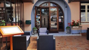 Un patio couvert avec un sol carrelé, un espace détente avec un fauteuil et un panneau d’affichage.