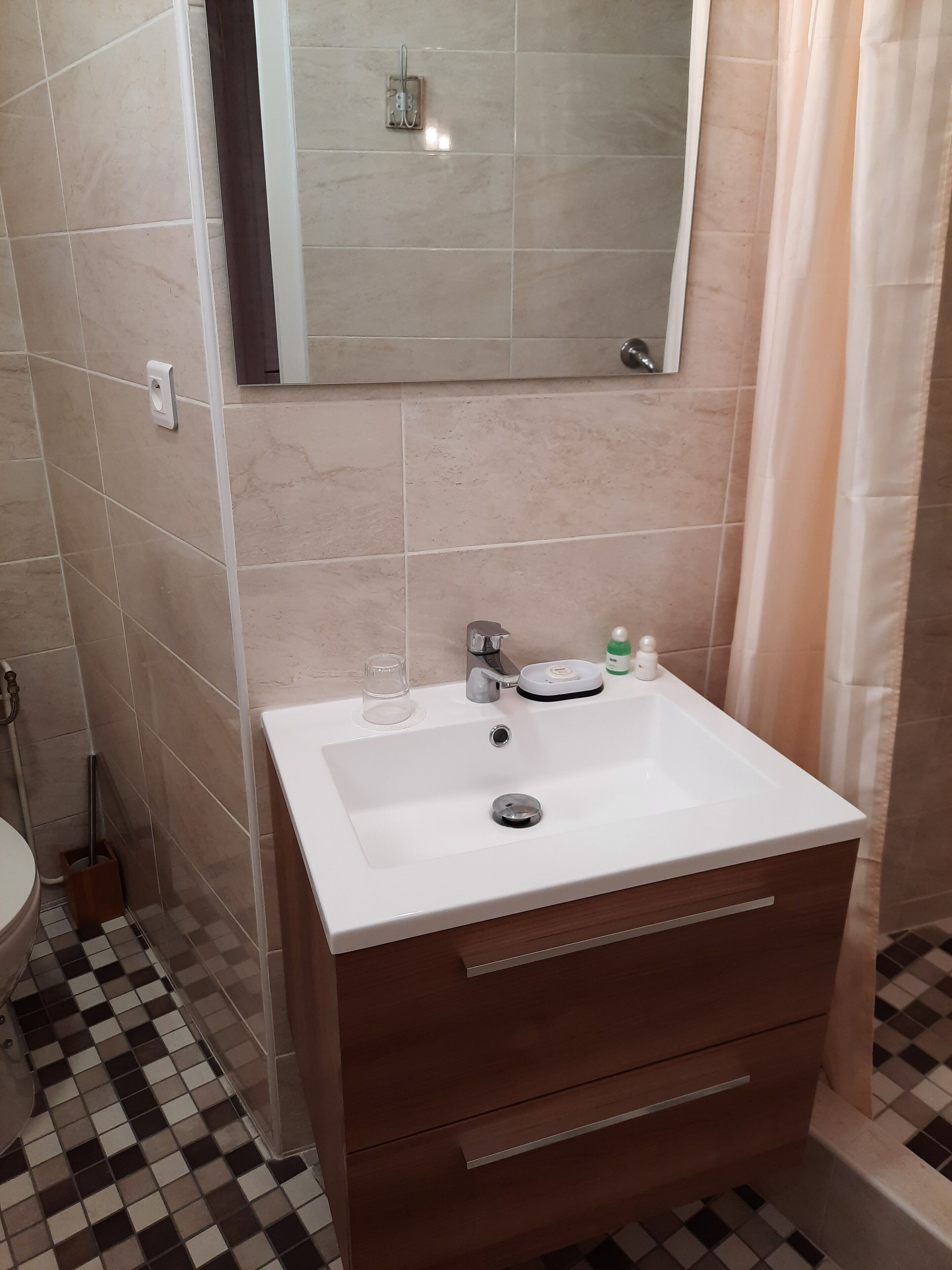 A bathroom with a white sink, a mirror, and a wooden cabinet.