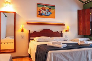 Een hotelkamer met een houten bed, twee bedlampen, een schilderij aan de muur en een houten garderobe.