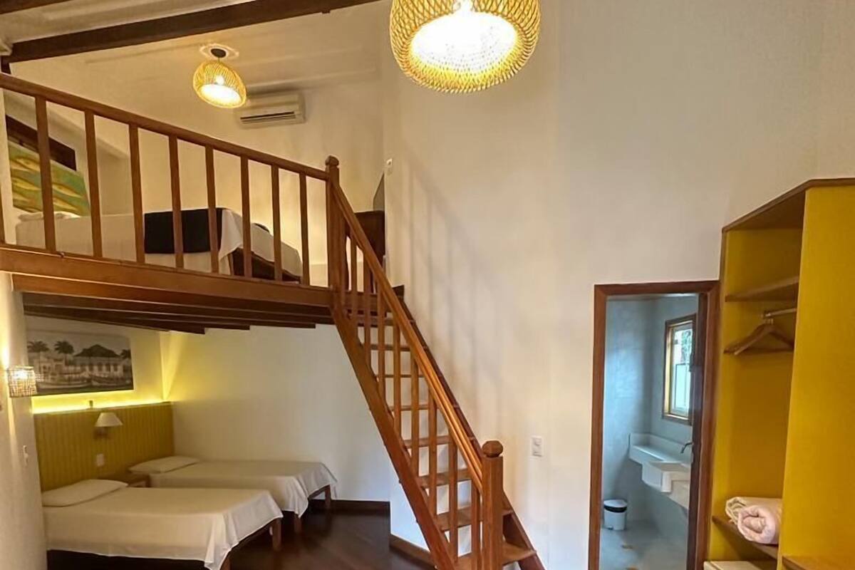A room with a wooden staircase, a bunk bed, and a yellow wardrobe.