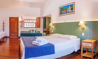 Habitación de hotel con cama, escritorio, silla, ventana con vista a un edificio y un cuadro en la pared.