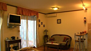 A living room with a television, sofa, coffee table, and a dining area with chairs. - Apartmani Znjan (Split)