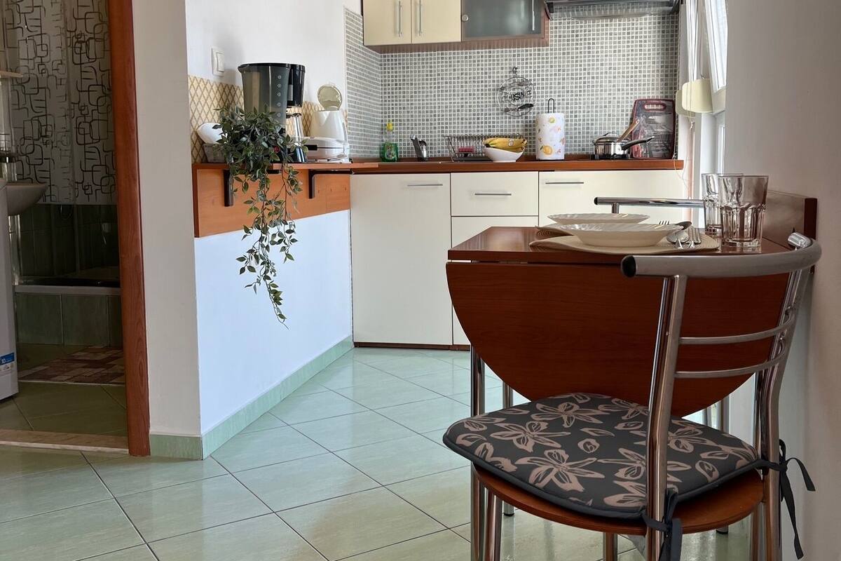 Eine moderne Küche mit weißen Schränken, einer gefliesten Spritzschutzwand und einem Essbereich mit einem Holztisch und Metallstühlen.