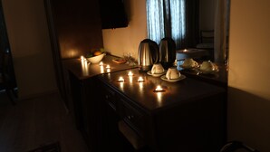 A dimly lit room with a wooden table set for tea, candles, and a bowl of fruit. - Villa Sofia (Istanbul)