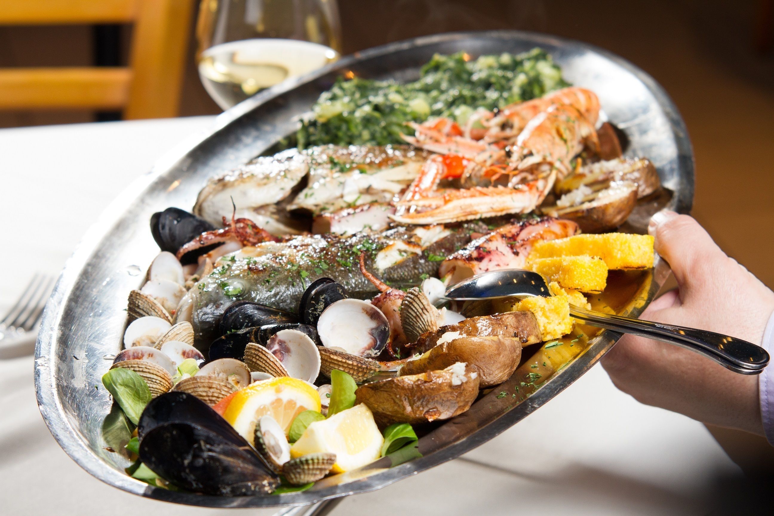A seafood platter with clams, mussels, and lobster, garnished with herbs and lemon slices.