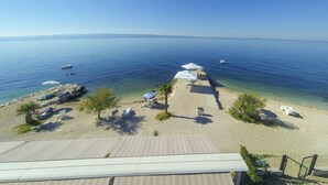 Une plage avec une eau d’un bleu limpide, des parasols et des chaises longues.