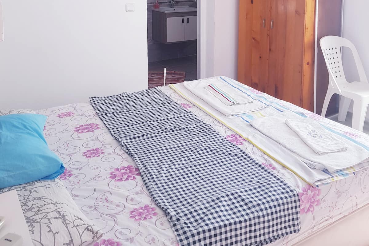 A bedroom with a bed, a wardrobe, a mirror, and a bathroom visible through an open door.