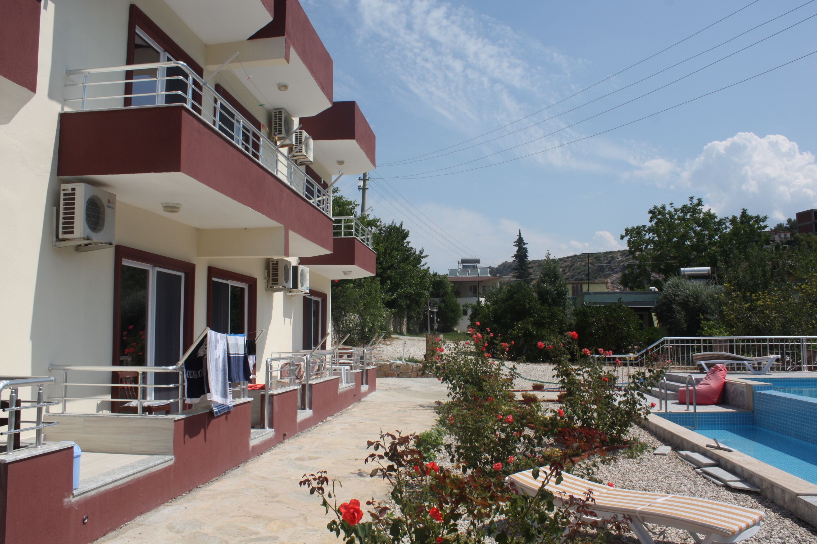 A multi-story building with balconies, a swimming pool, and outdoor seating.