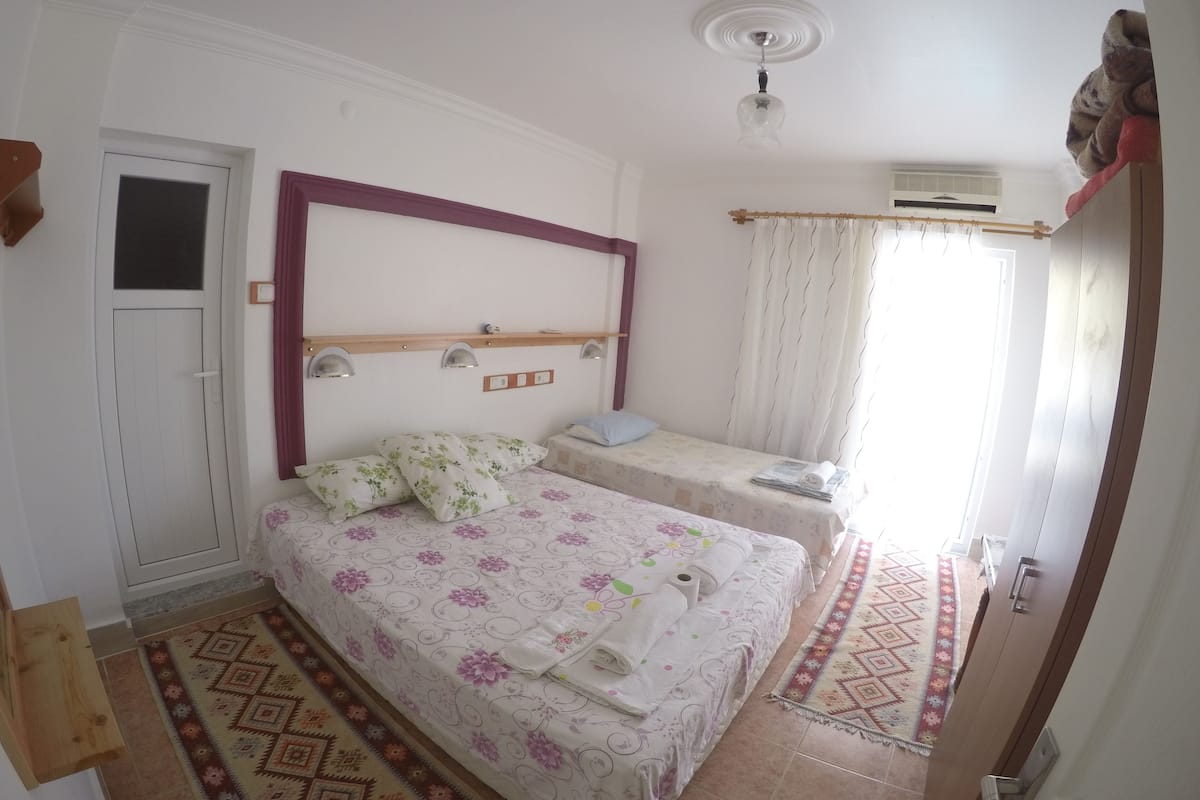 A bedroom with two beds, a wooden headboard, a ceiling fan, and a patterned rug.