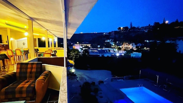 Ein Balkon mit Blick auf ein Schwimmbecken und die Skyline im Abenddämmerung.