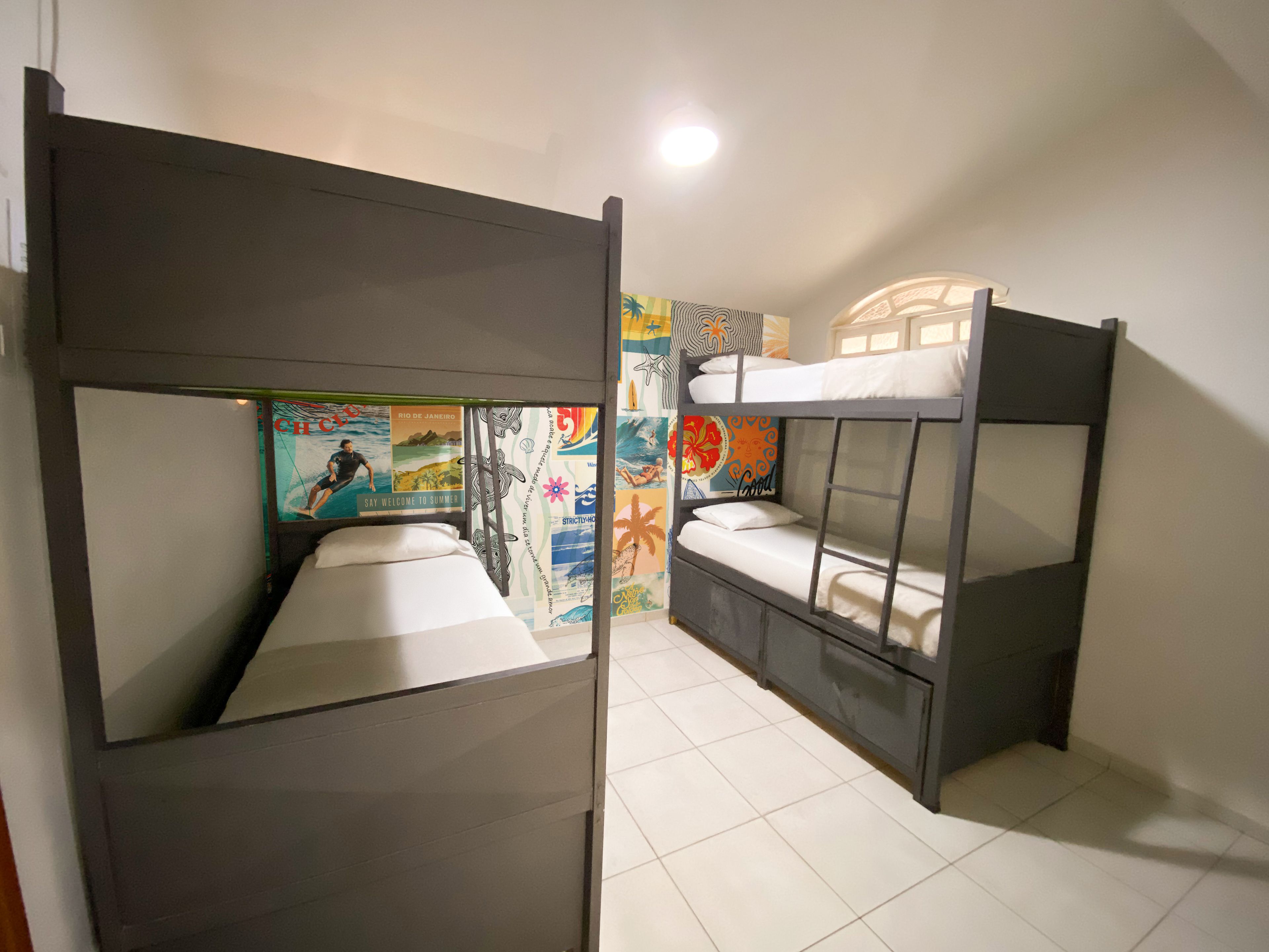 A room with bunk beds, a tiled floor, and colorful wall art.