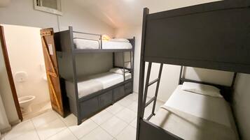 Quarto com beliche, sanitário e porta.