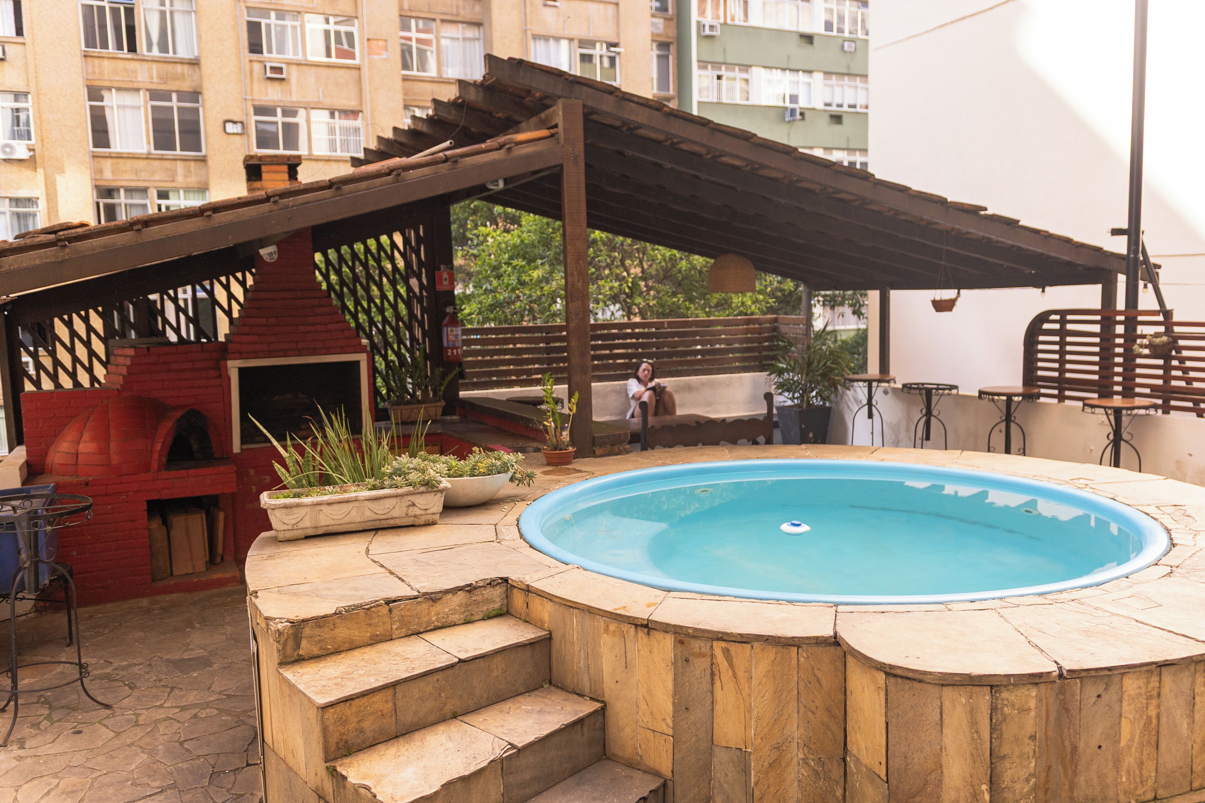 A hot tub with a wooden deck, a barbecue grill, and a covered patio area.