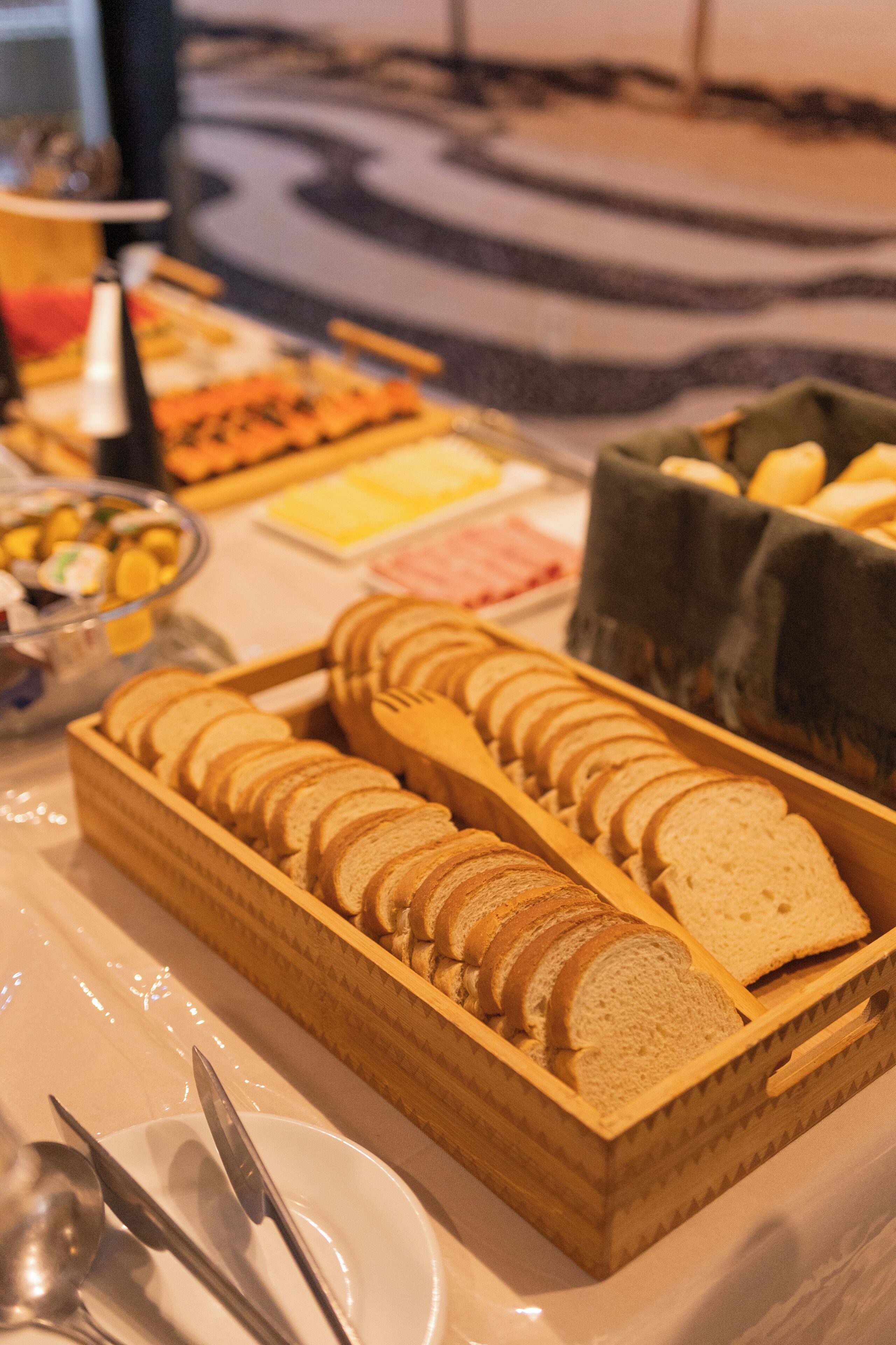 A buffet table with sliced bread, cheese, and other food items.