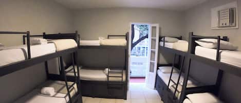 A dormitory room with bunk beds, a tiled floor, and a door leading outside.