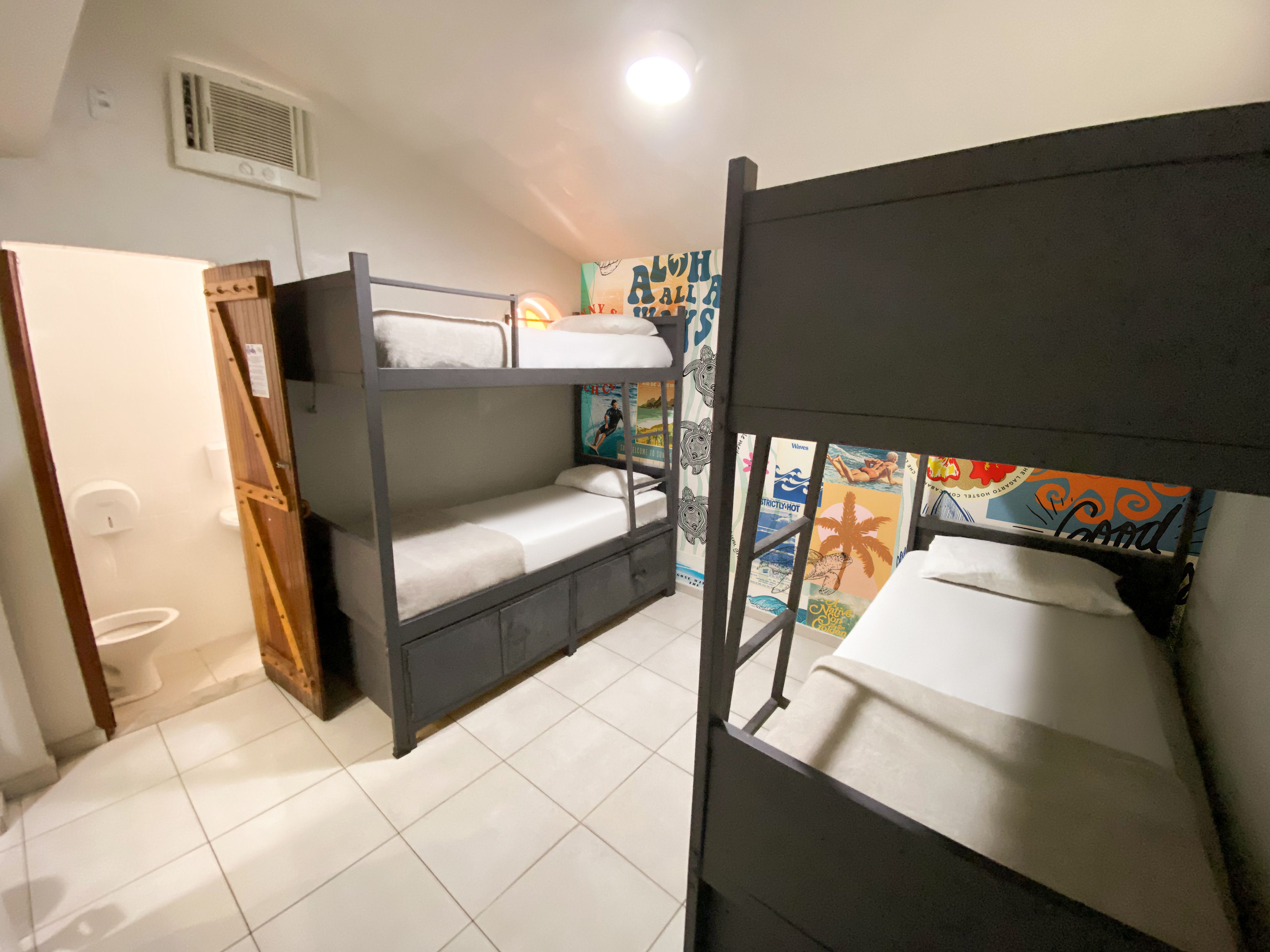A room with bunk beds, a toilet, and a shower.