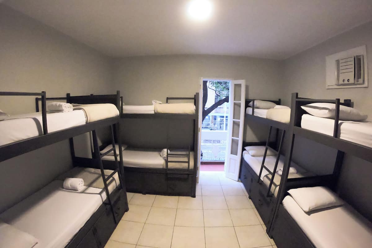A dormitory room with bunk beds, a tiled floor, and a door leading outside.