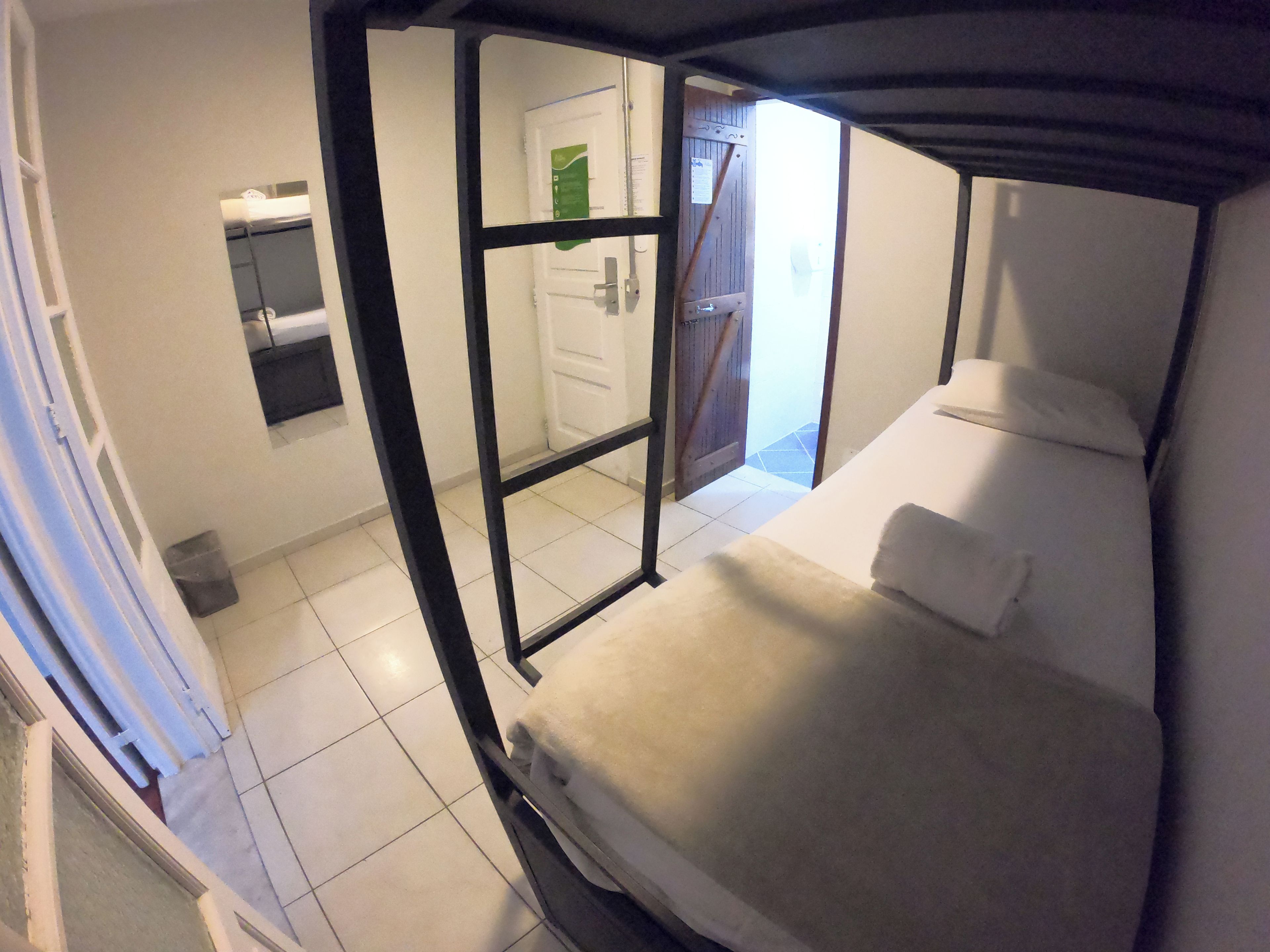 Una habitación con cama, una puerta y un ventanal pequeño.