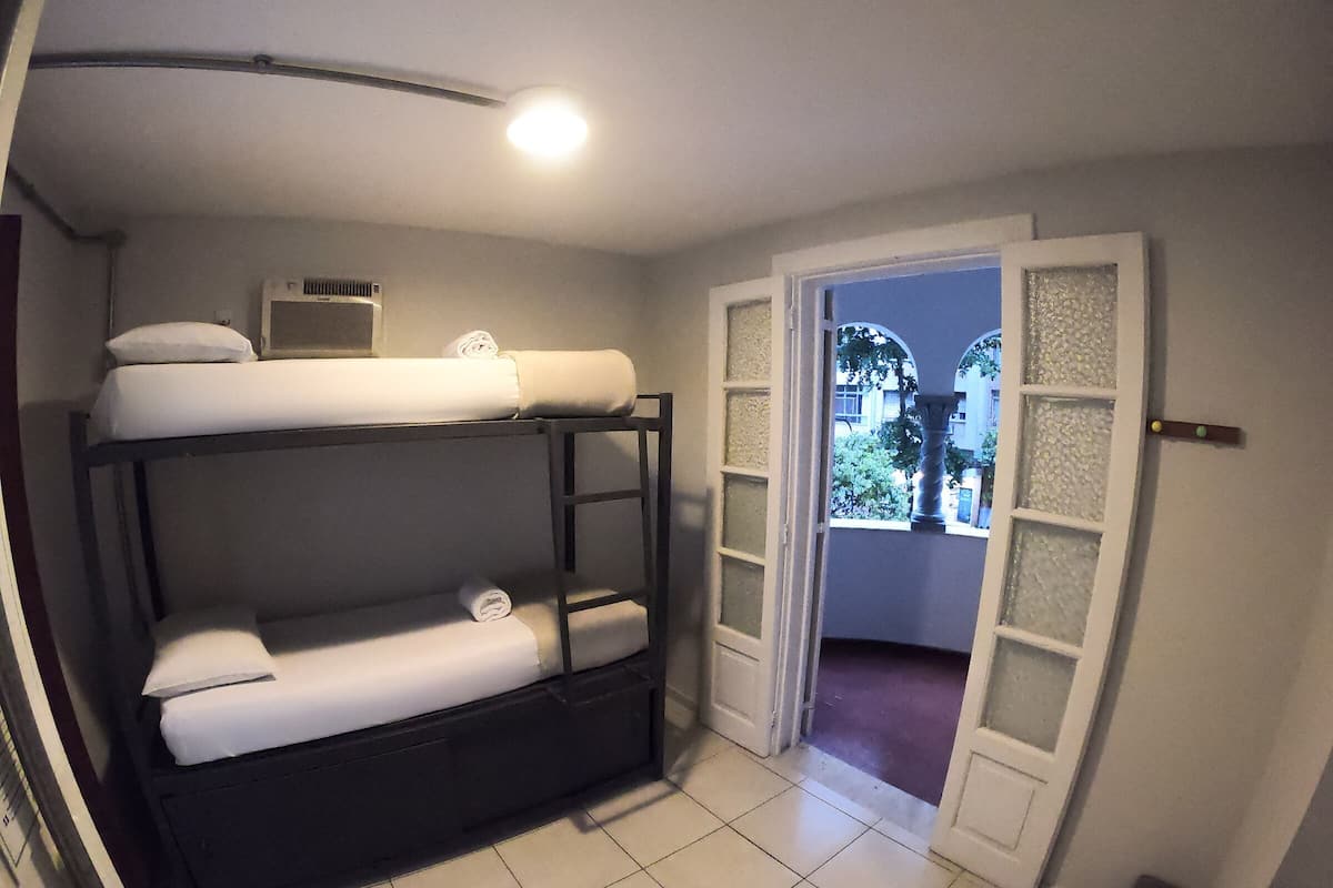 A room with bunk beds, a small table, and a window with a view of the outside.
