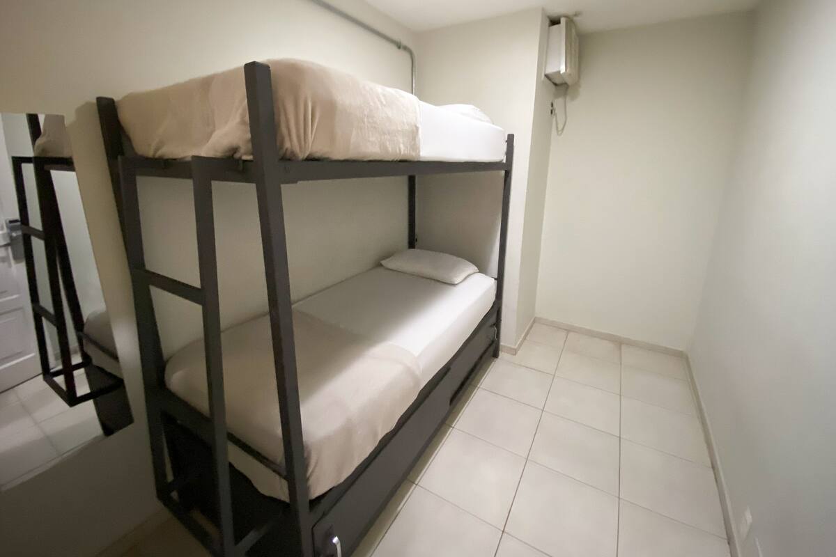 A bunk bed in a small room with white walls and a tiled floor.