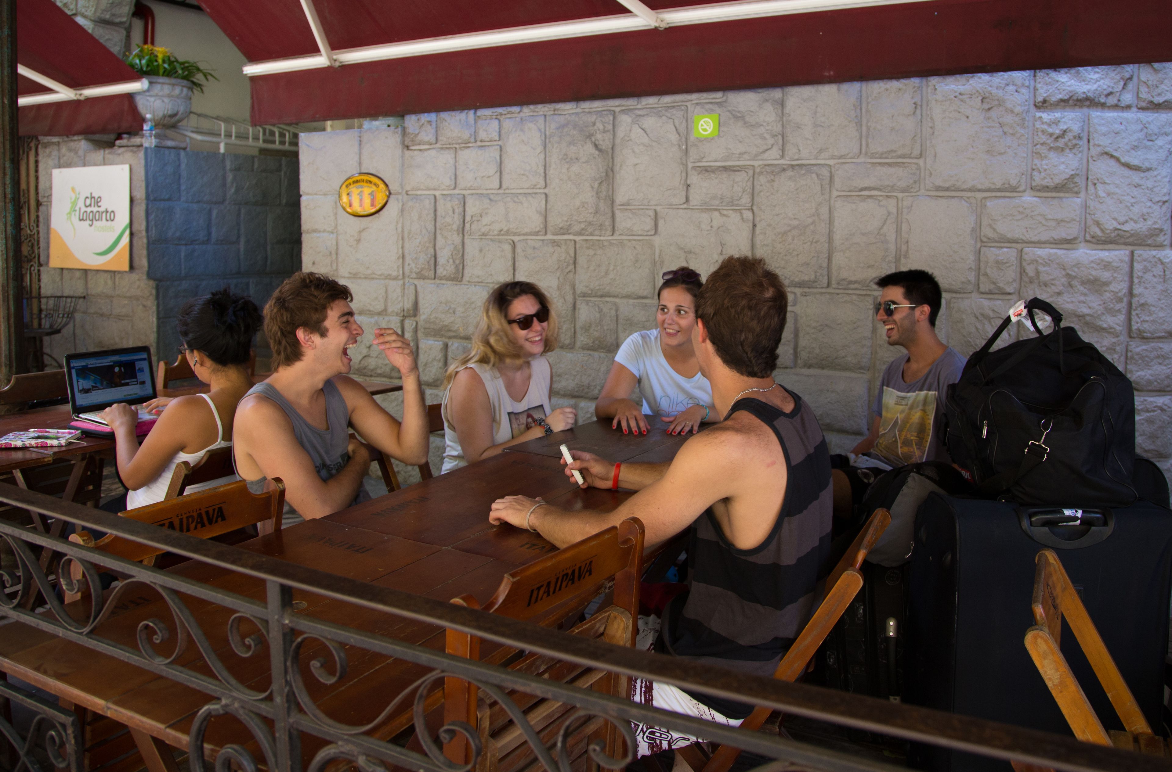 A group of people seated around a wooden table in a restaurant with stone walls and a red ceiling.
