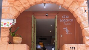 Una escalera lleva a la entrada de un hostal, con un letrero que dice 'che Lagarto hostels' y el número '111' en la pared.