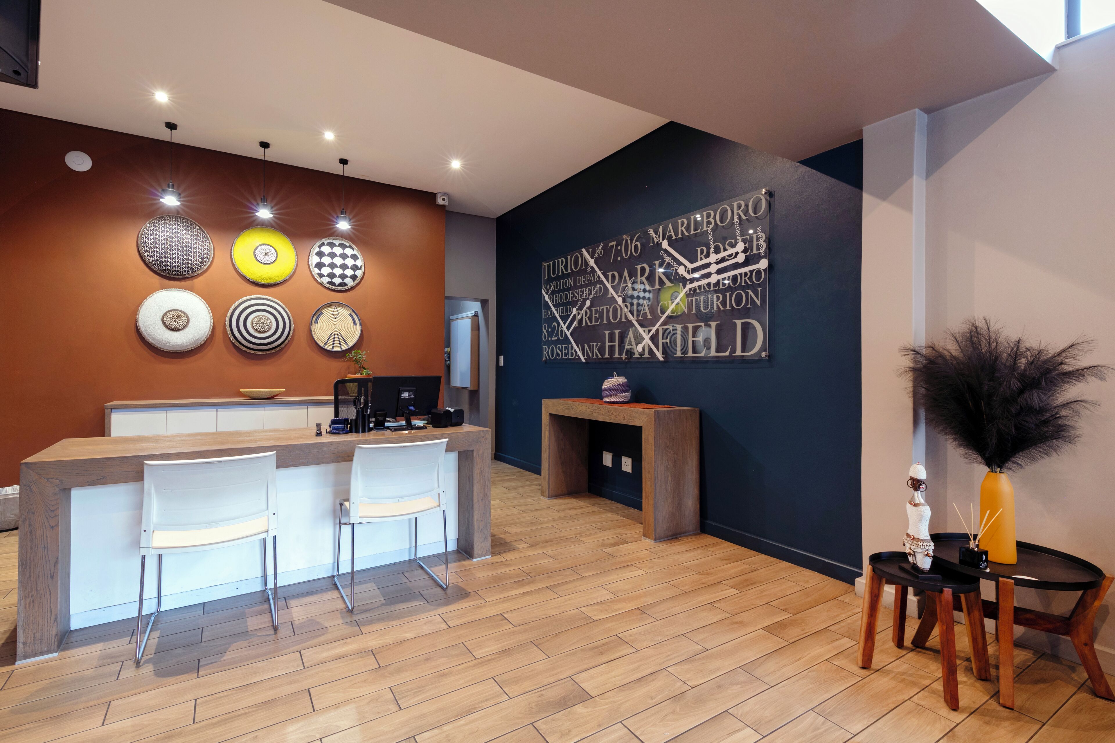 A modern reception area with a wooden reception desk, two white chairs, and a decorative wall with circular patterns.
