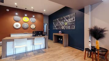 A modern reception area with a wooden reception desk, two white chairs, and a decorative wall with circular patterns.
