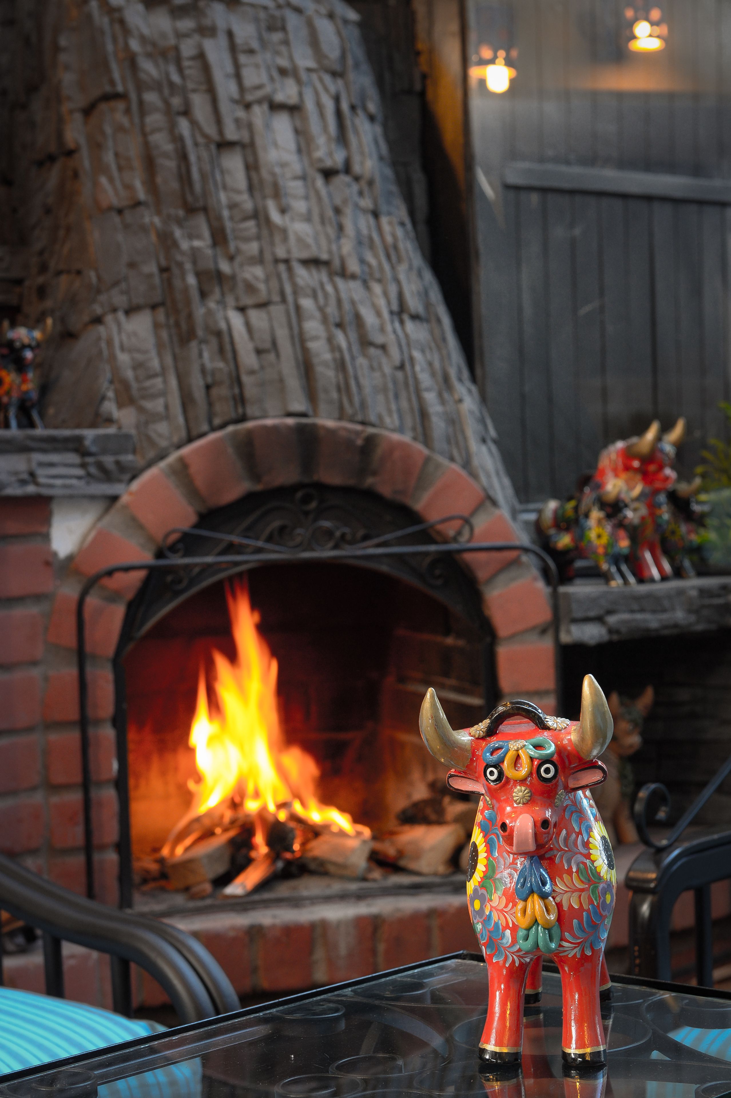 A decorative bull figurine in front of a brick fireplace with a fire burning.
